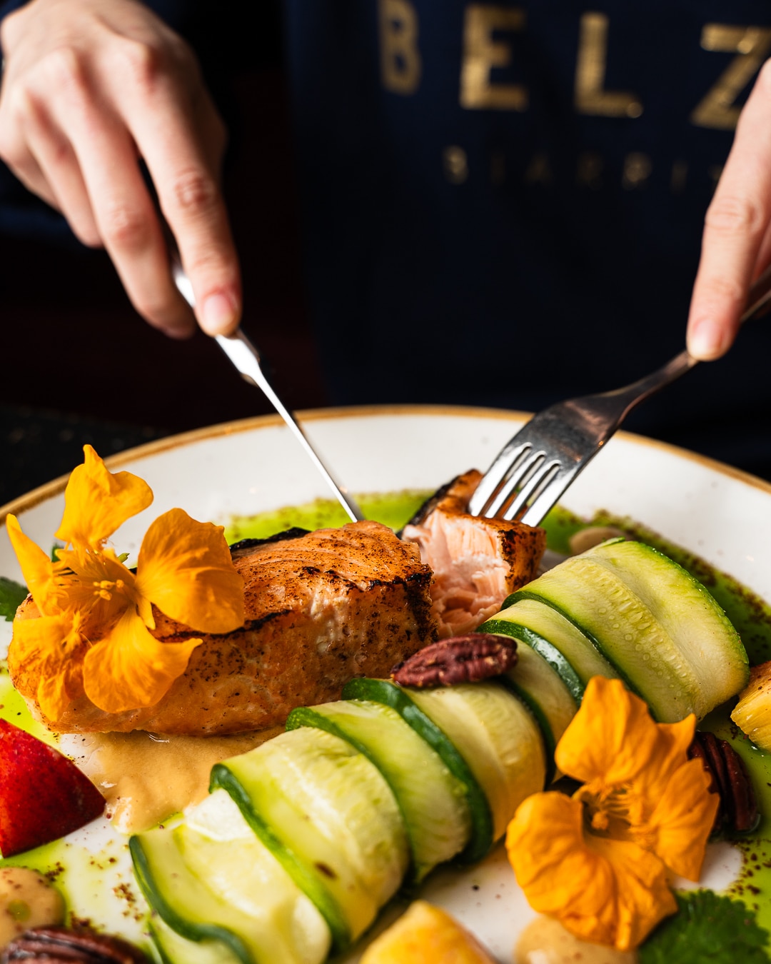 Personne coupant saumon, courgettes et capucines